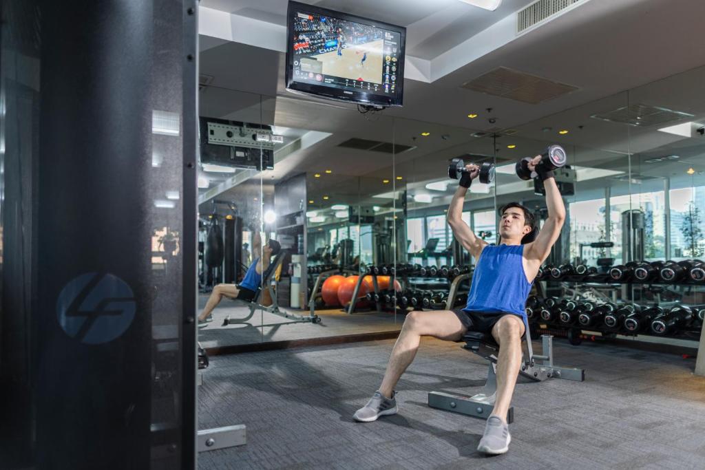A mirrored fitness room with free weights, benches and a television.