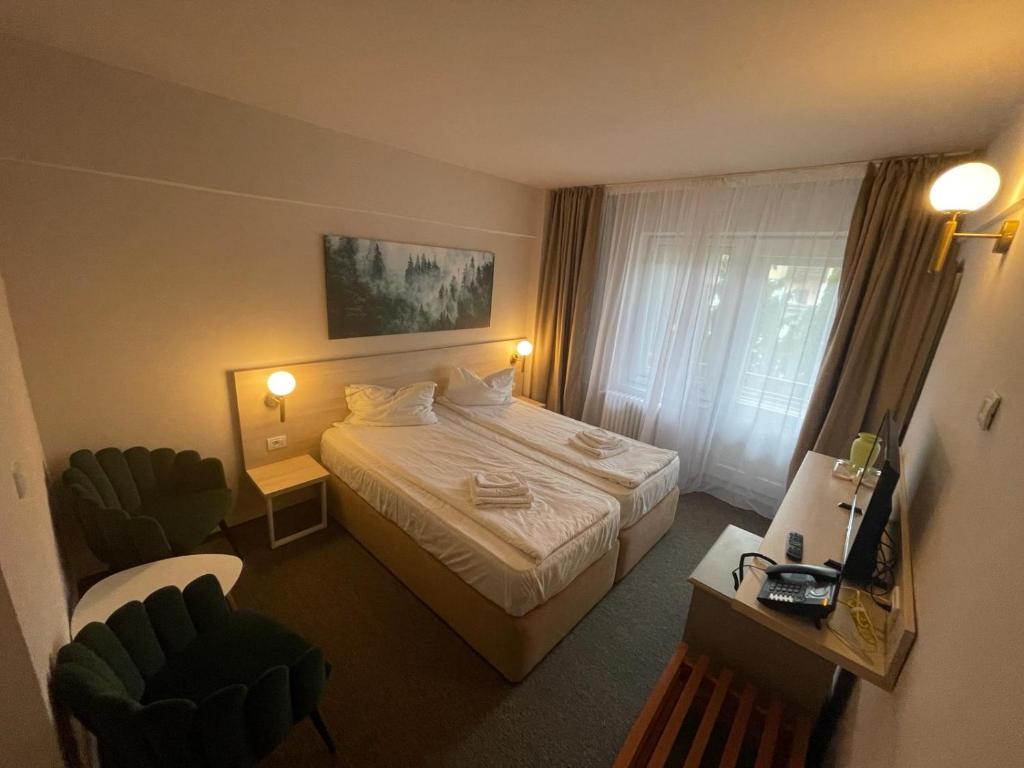 a hotel room with a bed and two chairs at Bacolux Santis, Covasna in Covasna