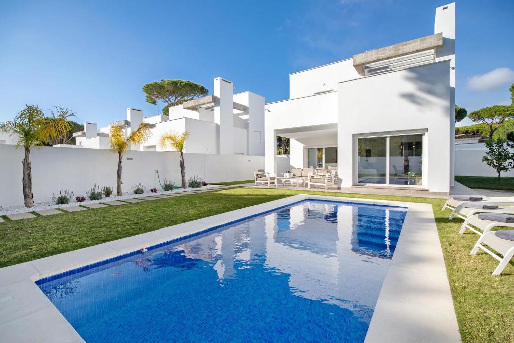 een wit huis met een zwembad ervoor bij Villa moderna en Chiclana in Chiclana de la Frontera