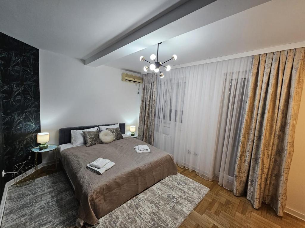 ein Schlafzimmer mit einem großen Bett und einem Kronleuchter in der Unterkunft Apartman Florida in Kragujevac