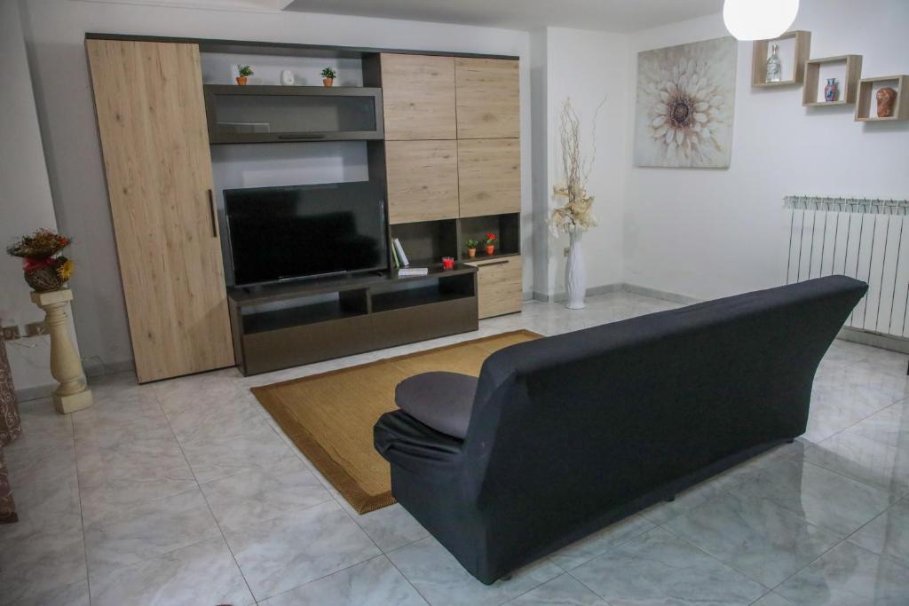 un salon avec un canapé noir et une télévision dans l'établissement TARANTA HOUSE - Notte della Taranta casa con giardino, à Melpignano