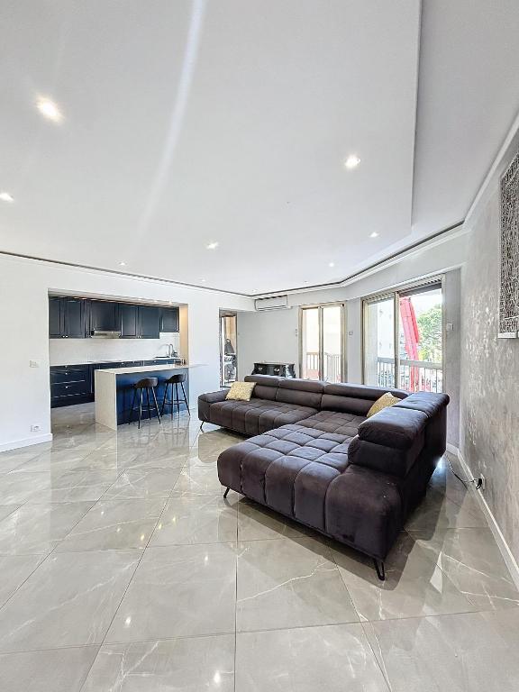 Il comprend un grand salon avec un canapé et une cuisine. dans l'établissement Résidence l'Empire, à Cannes