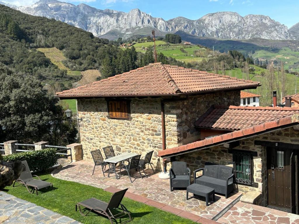 a stone house with a table and chairs and mountains at Viviendas Rurales la Fragua in Aliezo