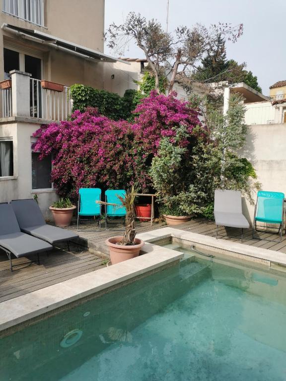 - une piscine avec des chaises et des fleurs à côté d'un bâtiment dans l'établissement Résidence des Abeilles, à Avignon