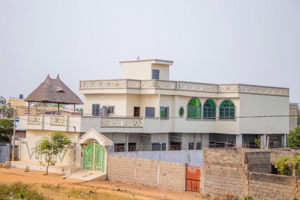 ein großes weißes Gebäude mit grünen Türen und einem Zaun in der Unterkunft Résidence Maronne in Porto-Novo