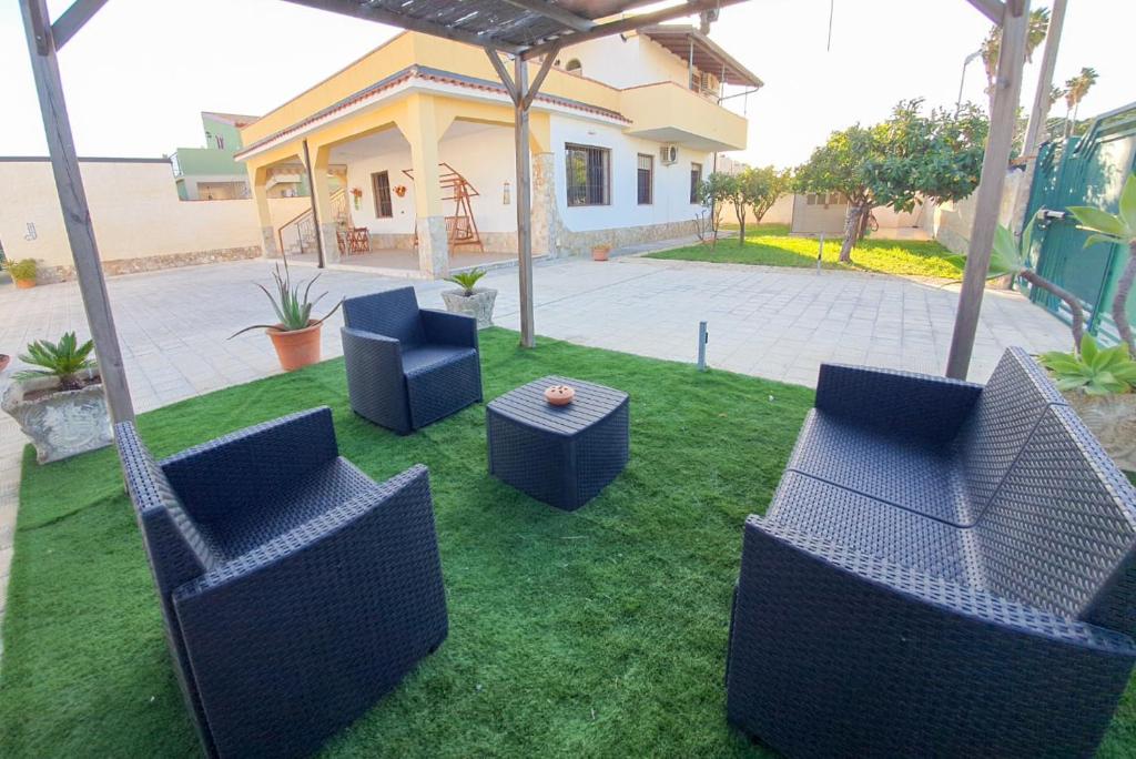 un cortile con sedie e tavolo e una casa di Villa La Sosta - 150m dal mare - Patio Privato e Areal Relax ad Arenella