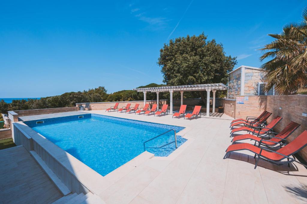 a swimming pool with lounge chairs and a swimming pool at Royal Apartments in Novalja