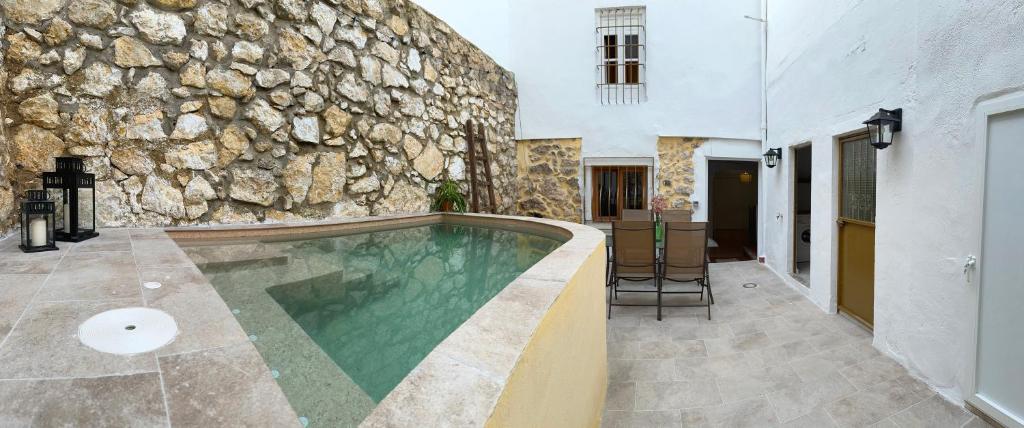 una piscina frente a una pared de piedra en CASA MARÍA LA ROMANA, en Torres