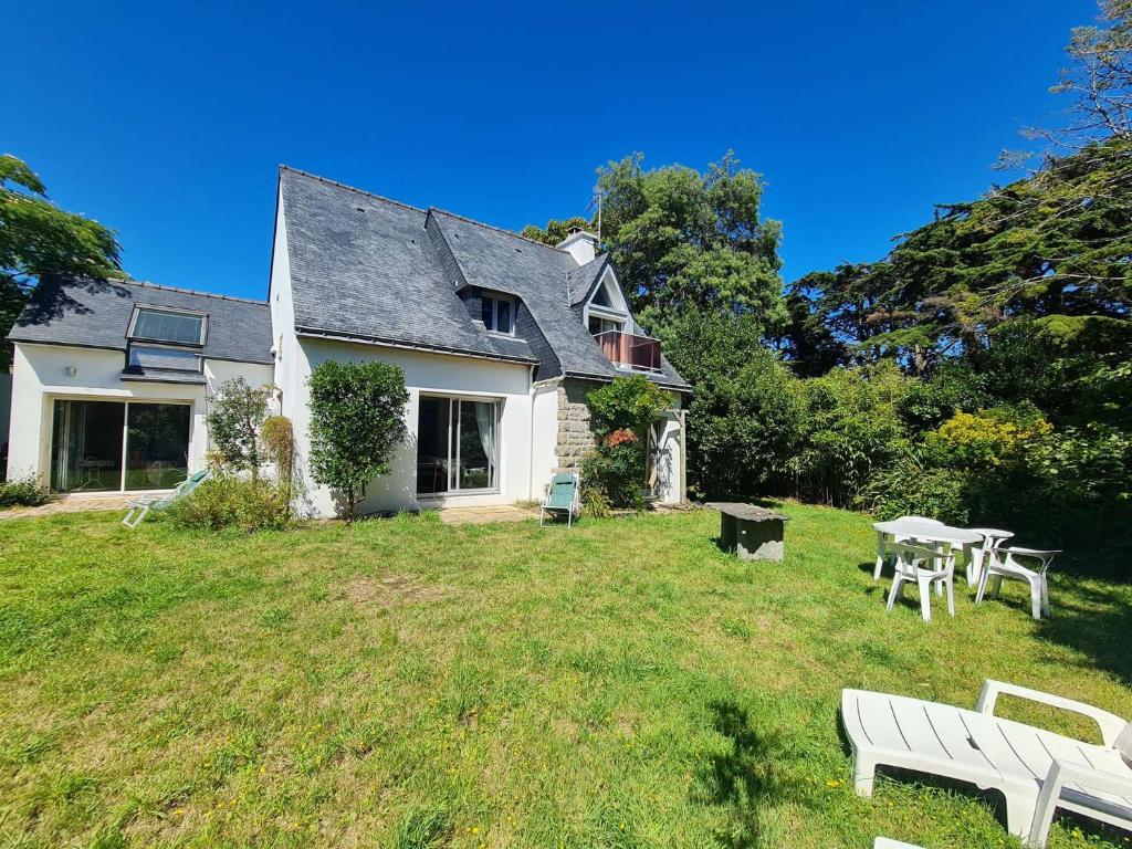 uma casa com um quintal com uma mesa e bancos em Ref 067 Maison proche golfe du Morbihan pour six à huit personnes à louer pour les vacances em Arzon