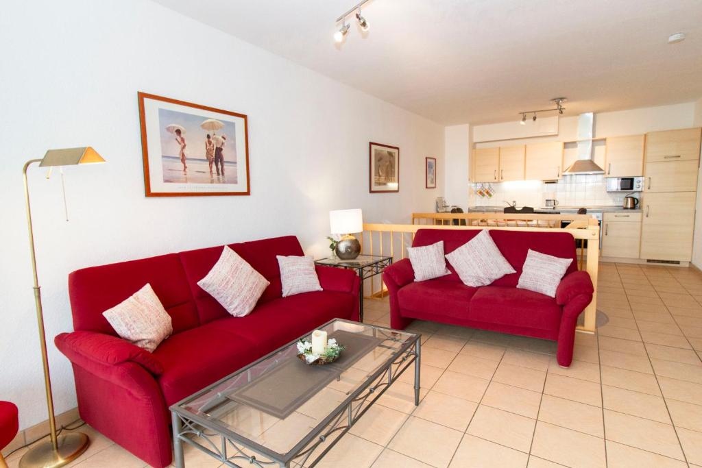 uma sala de estar com dois sofás vermelhos e uma cozinha em Nordseeblick 5 em Cuxhaven
