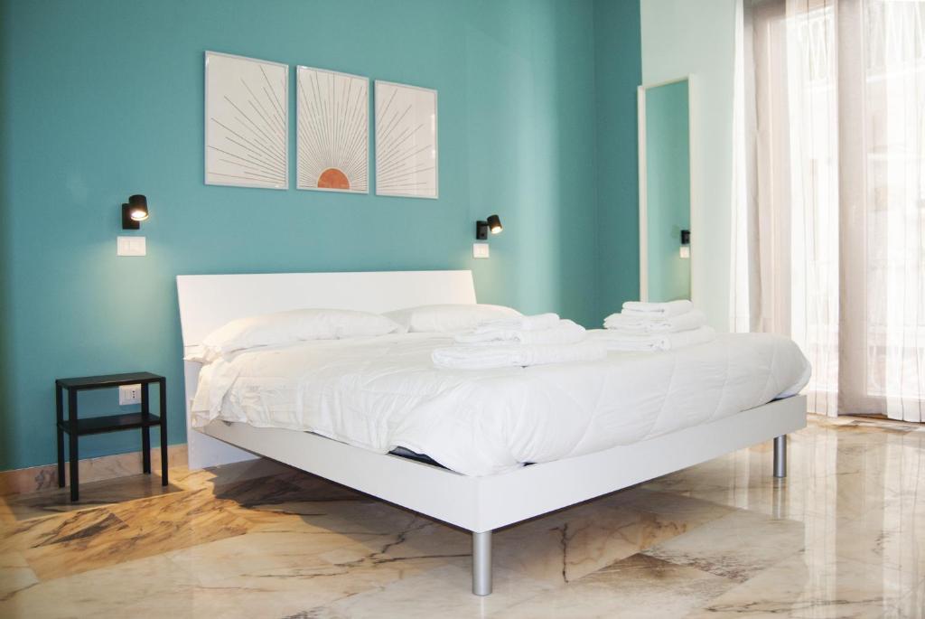 Cama blanca en habitación con pared azul en Le Sere, en Reggio Calabria