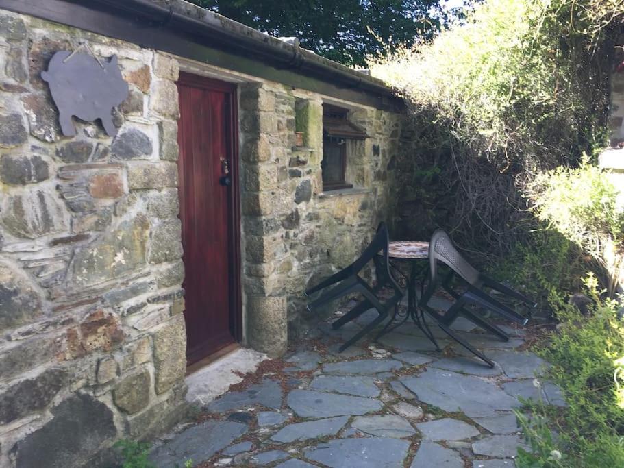 a stone building with a bench next to a red door at Homer Old Spot in Marytavy