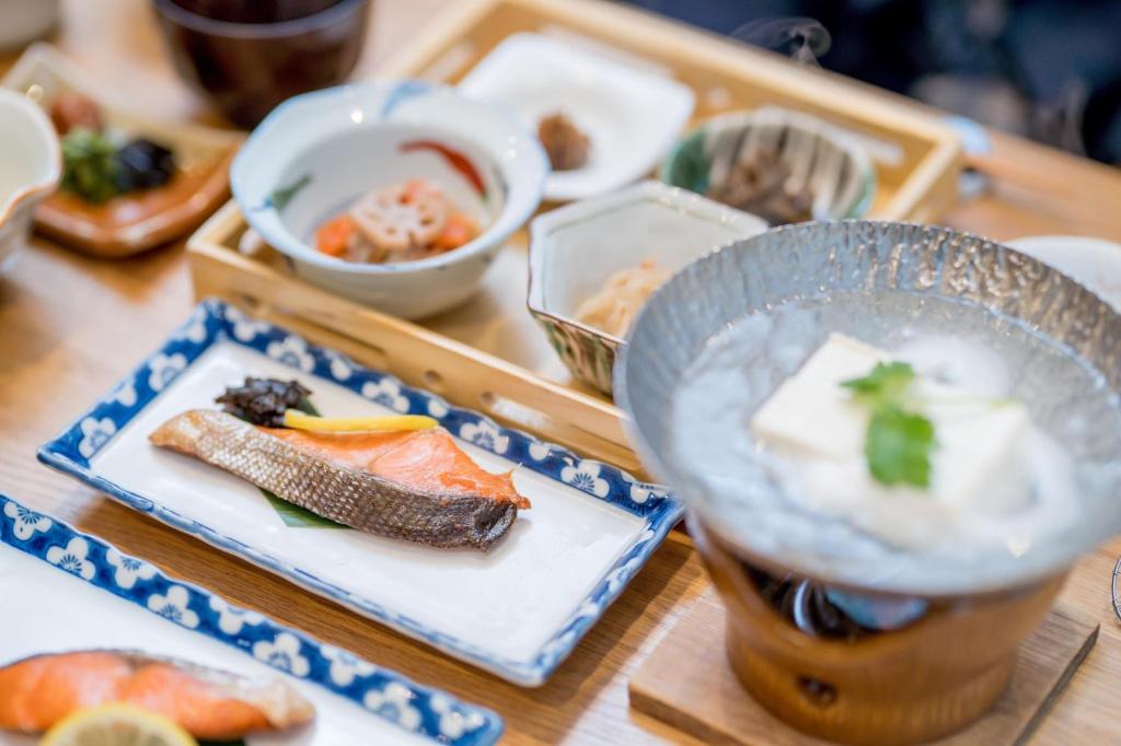 une table en bois avec des assiettes de nourriture et une boisson dans l'établissement Ryokan Ryokufuso, à Kyoto