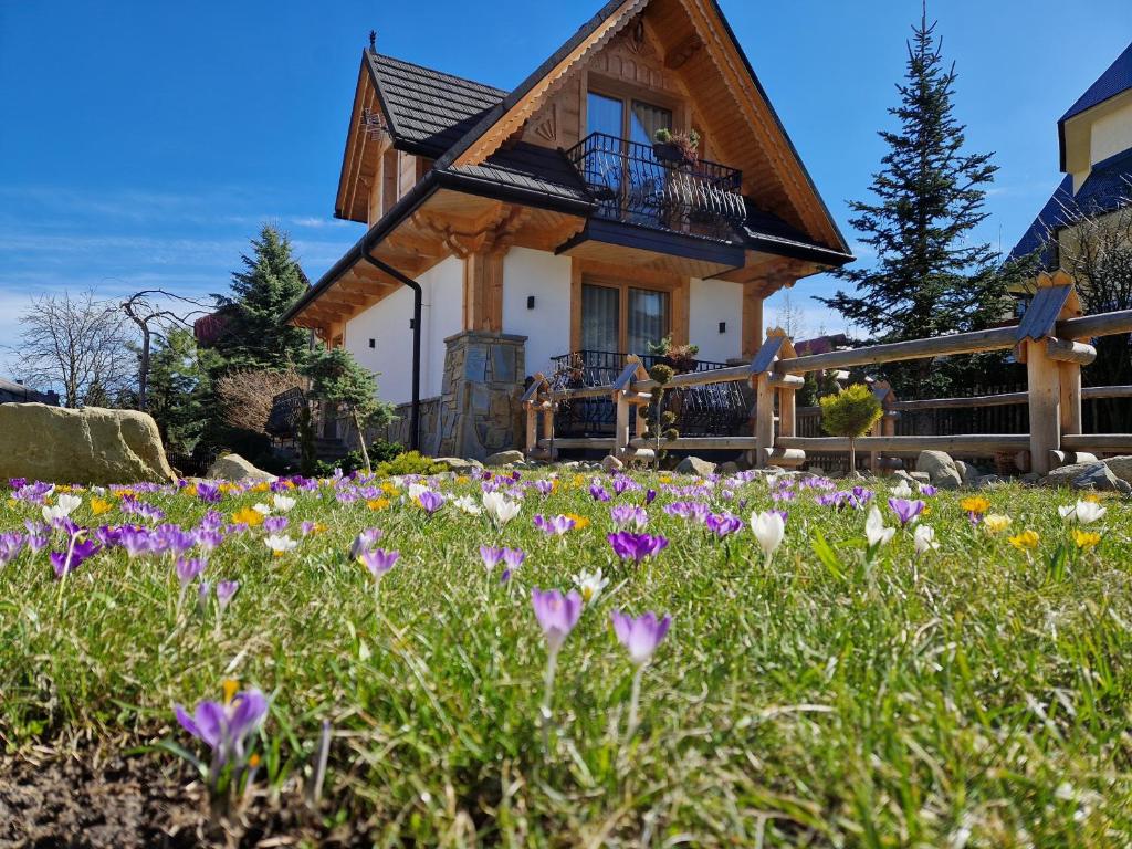 a house with a field of flowers in front of it at Apartamenty BENITA in Zakopane