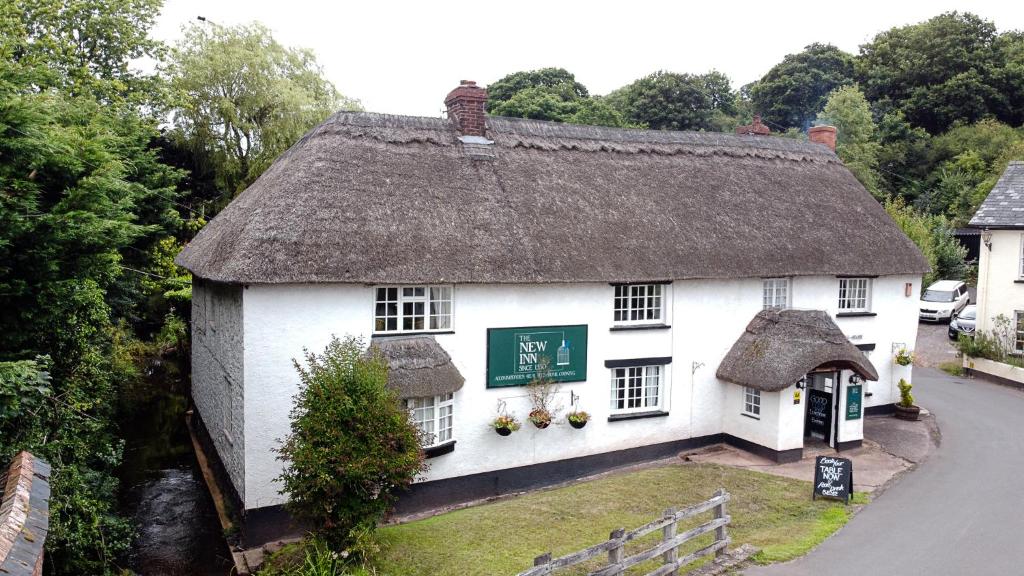 Ce cottage blanc ancien dispose d'un toit de chaume. dans l'établissement New Inn, à Crediton