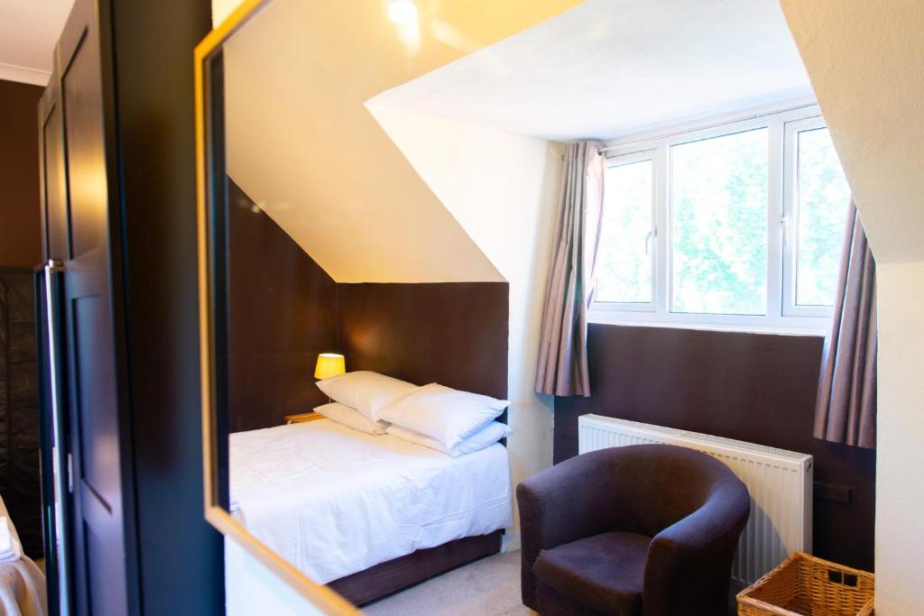 sypialnia z łóżkiem, krzesłem i lustrem w obiekcie Rare London 6bedroom House w mieście South Norwood