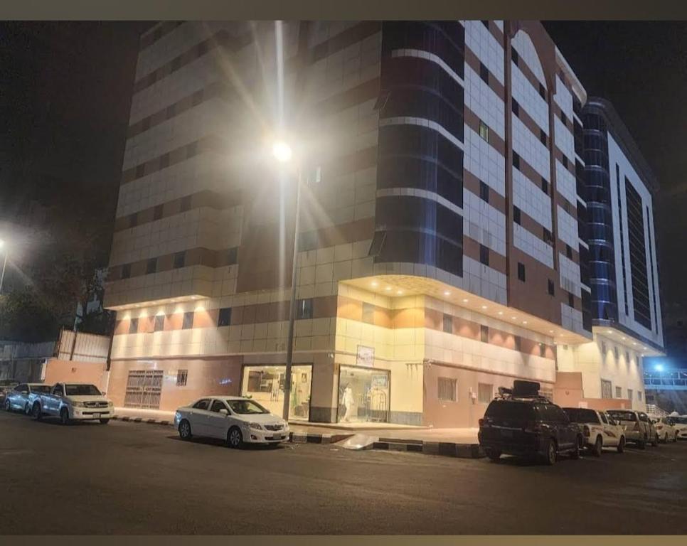 فندق البركة رويال في مكة المكرمة: مبنى فيه سيارات تقف في موقف السيارات في الليل