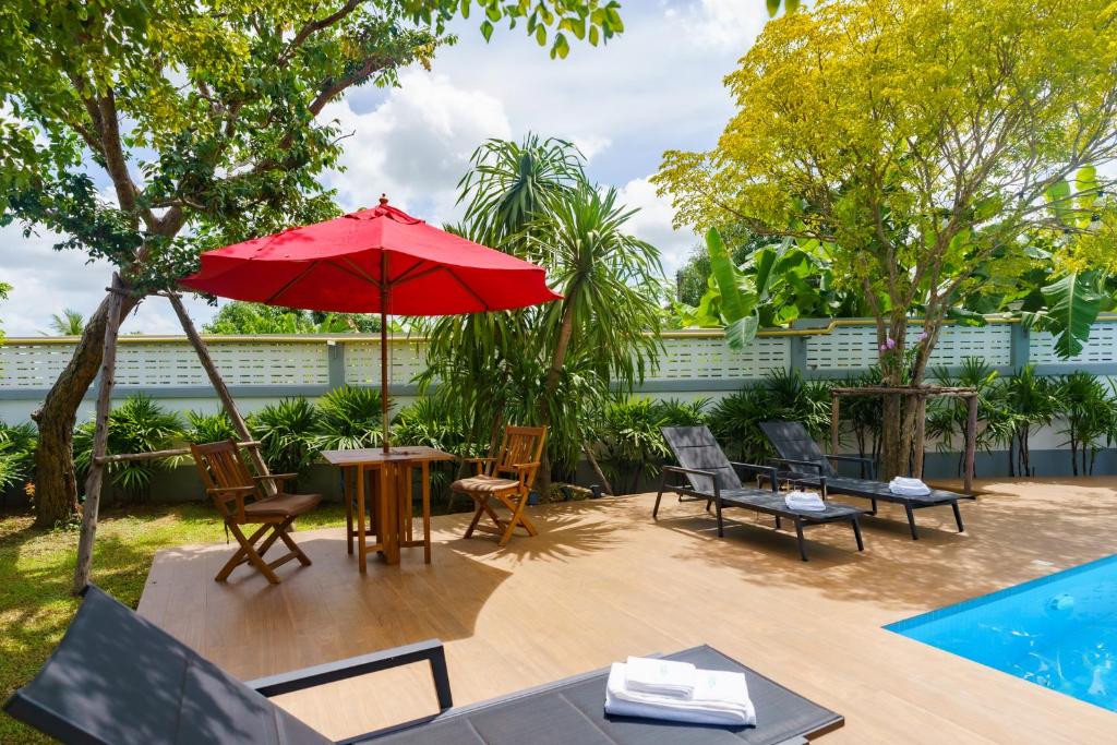 un patio con mesa, sillas y sombrilla roja en Baan Nern Khao Resort Pattaya en Ban Huai Yai