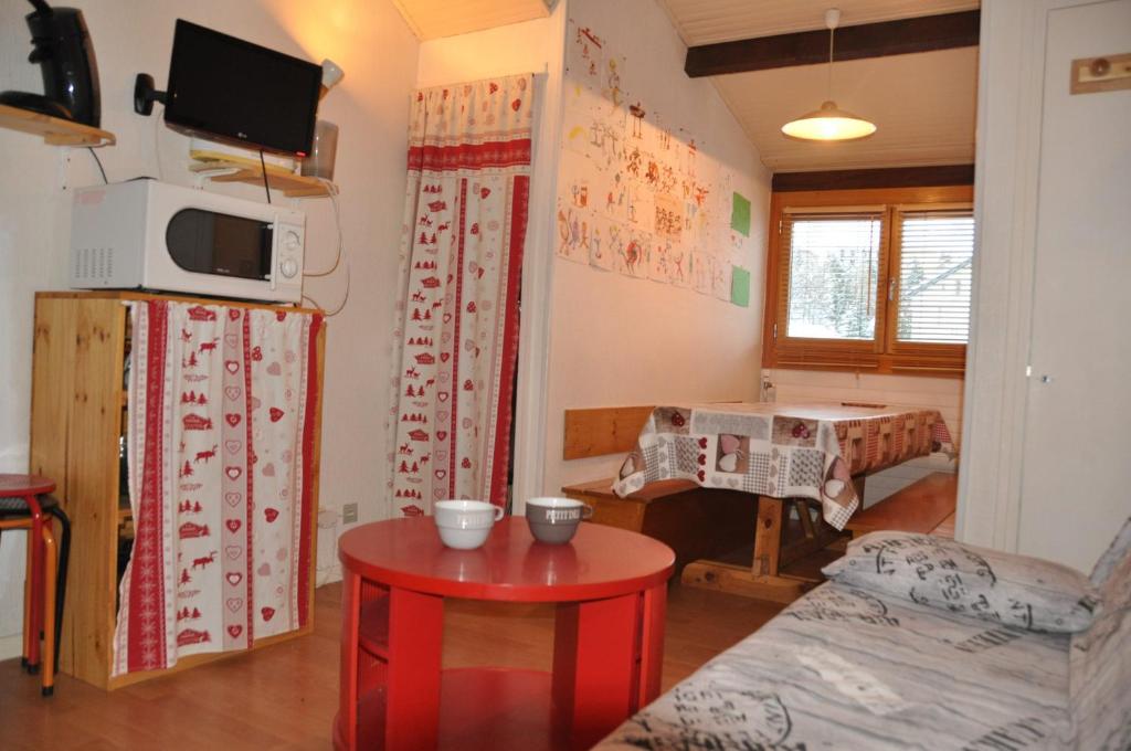 uma sala de estar com uma mesa vermelha num quarto em Olympe - 104 - Studio - 4 pers em Les Deux Alpes