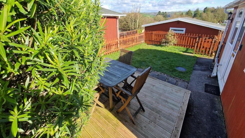 a wooden deck with a bench in a backyard at The Lookout - Chalet 32 in Carmarthen