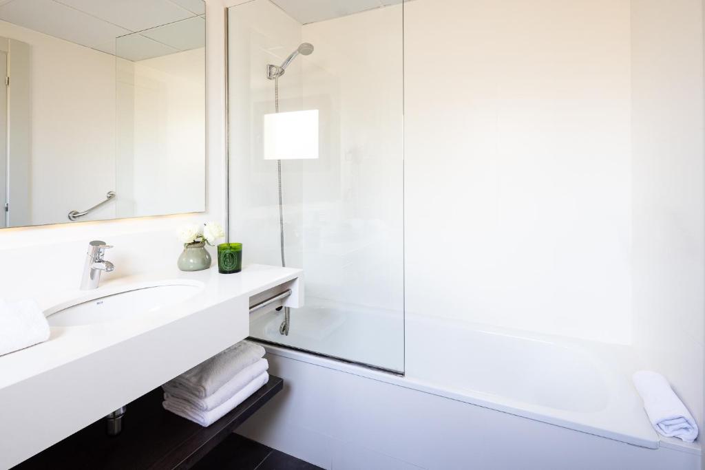 a white bathroom with a sink and a shower at Arc La Rambla in Barcelona