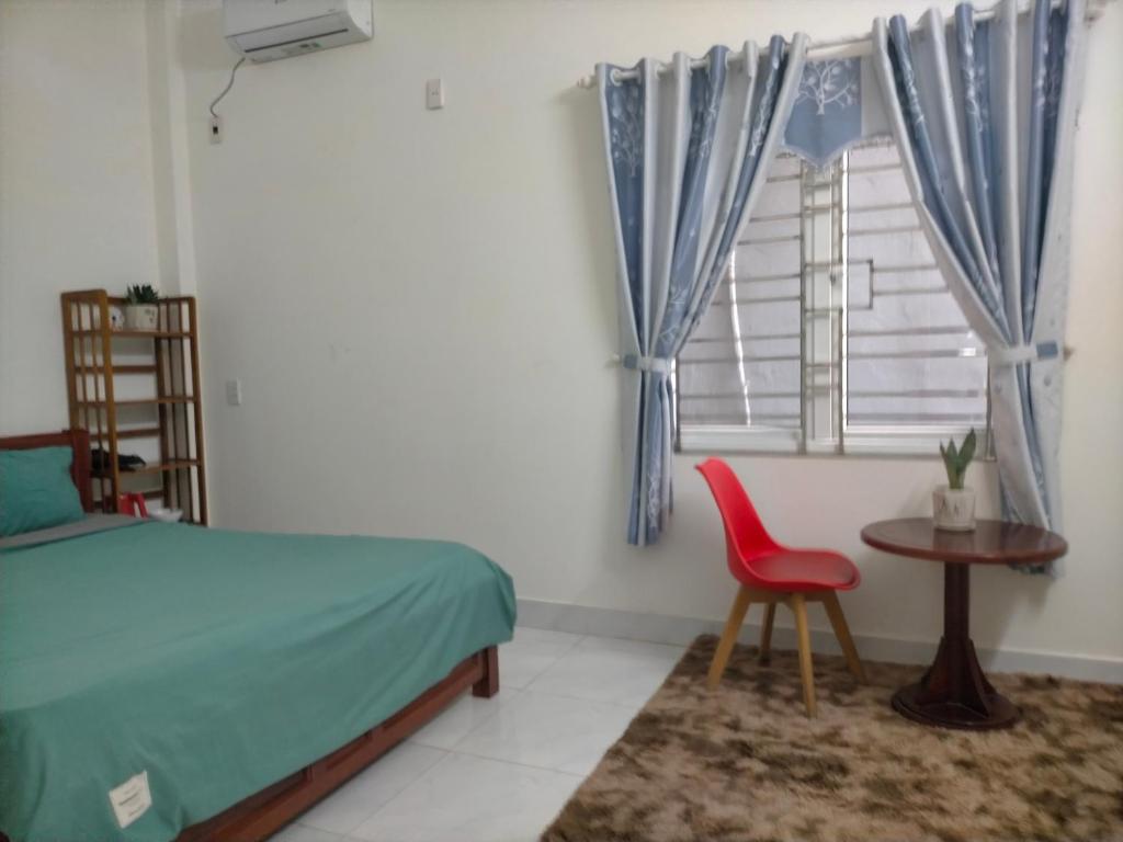 1 dormitorio con cama, silla roja y ventana en TN's House, en Da Nang