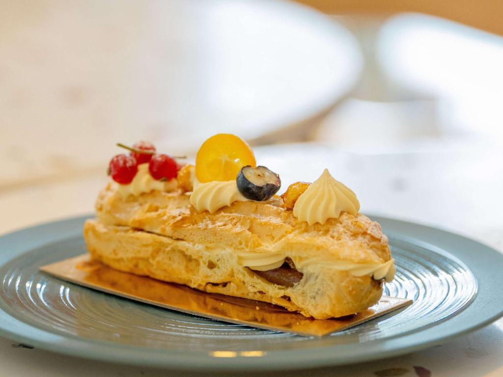 a piece of cake with fruit on a blue plate at Novotel Istanbul Bosphorus Hotel in Istanbul