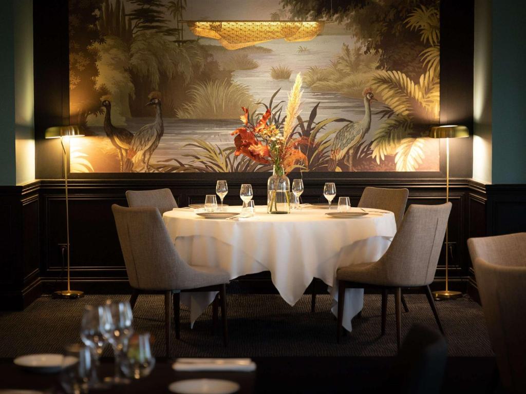 - une table dans un restaurant avec un vase de fleurs dans l&#39;établissement Hôtel Mercure Rochefort La Corderie Royale, à Rochefort