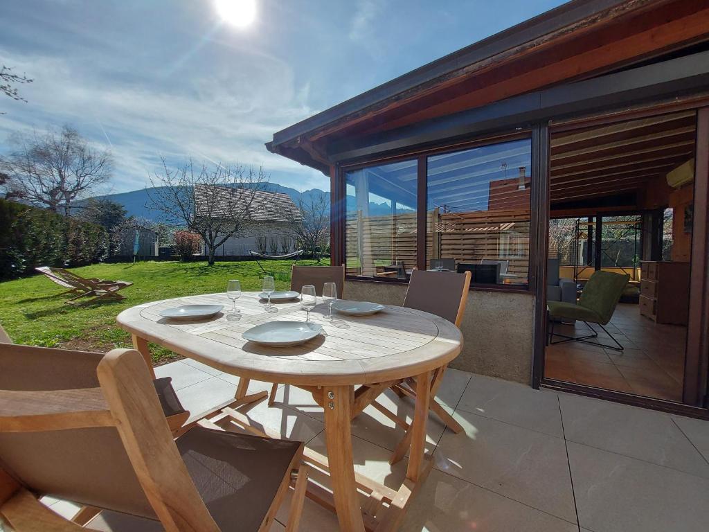 a wooden table and chairs on a patio at Entre lac et montagne, côté calme, spacieux 3 pièces avec grand jardin in Saint-Jorioz