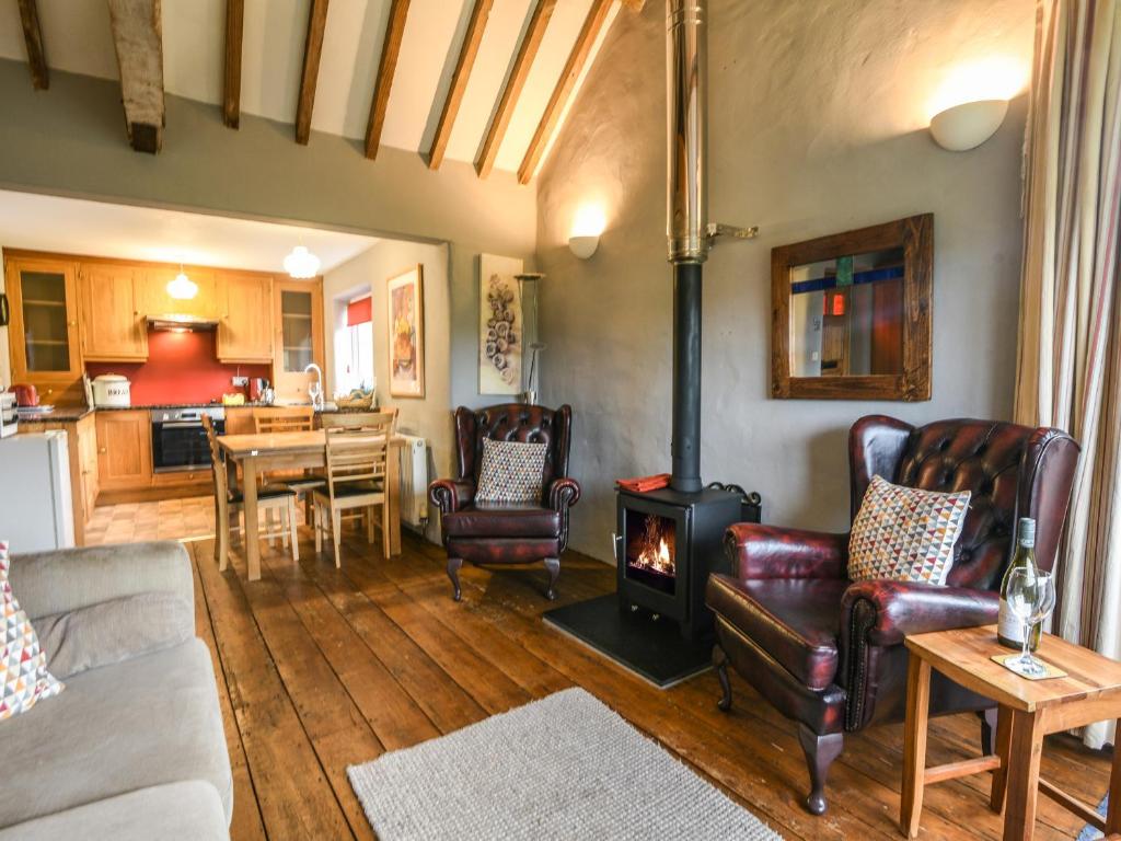 a living room with a wood stove and a kitchen at The Old Dairy in Bridport