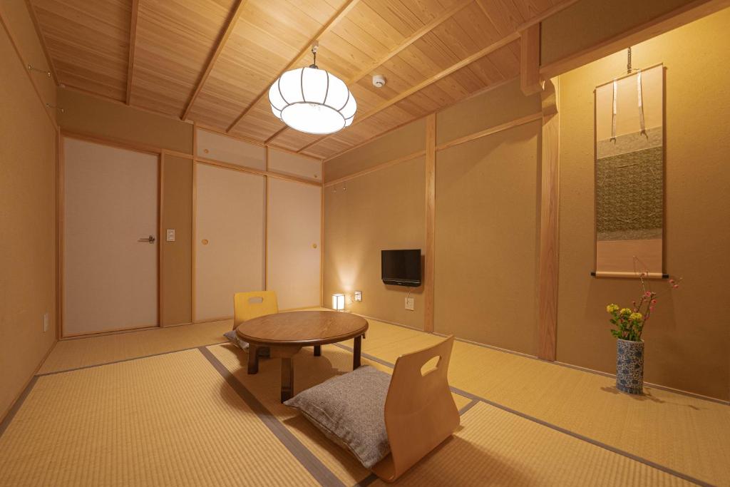 Saju Kyoto 茶住 京都 في كيوتو: غرفة مع طاولة وكراسي وتلفزيون