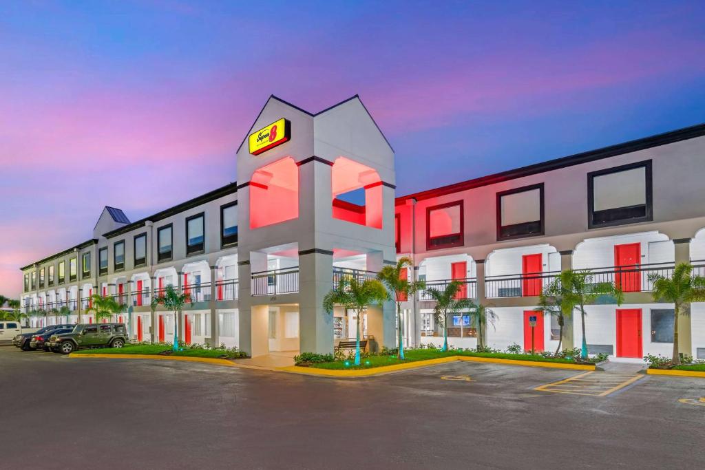 ein Hotel mit Uhrturm auf einem Parkplatz in der Unterkunft Super 8 by Wyndham Orlando Near Florida Mall in Orlando