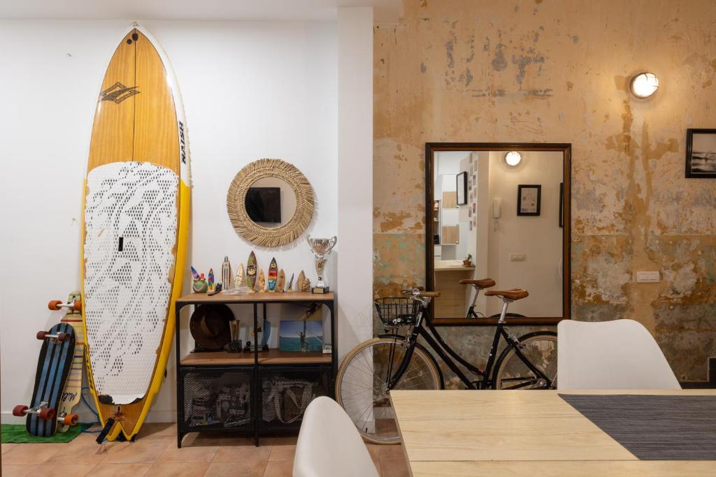 uma prancha de surf encostada a uma parede ao lado de uma sala de jantar em Kite & Surf Nomad House em Las Palmas de Gran Canaria