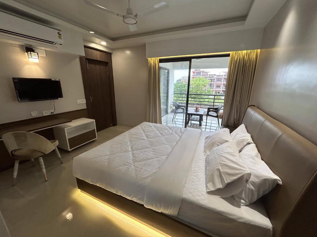 um quarto com uma cama, uma secretária e uma televisão em The Pearl Club Resort em Santiniketan