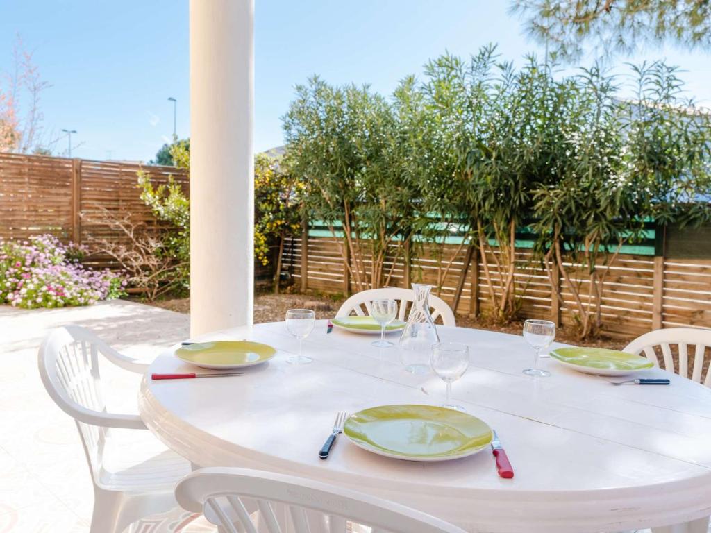 - une table blanche avec des assiettes et des verres à vin dans l'établissement Appartement T4 Rez-de-Jardin Proche Plage, Terrasse, Parking, 3 Chambres, Résidence Sécurisée - FR-1-409-224, à Narbonne