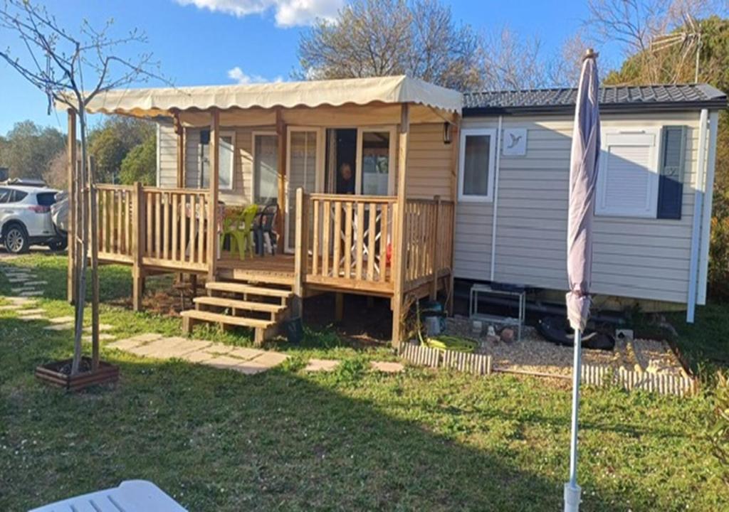 a tiny house with a porch and a deck at Mobil-home (Clim, Tv, Lv)- Camping Lac des Rêves 4* - 009 in Lattes