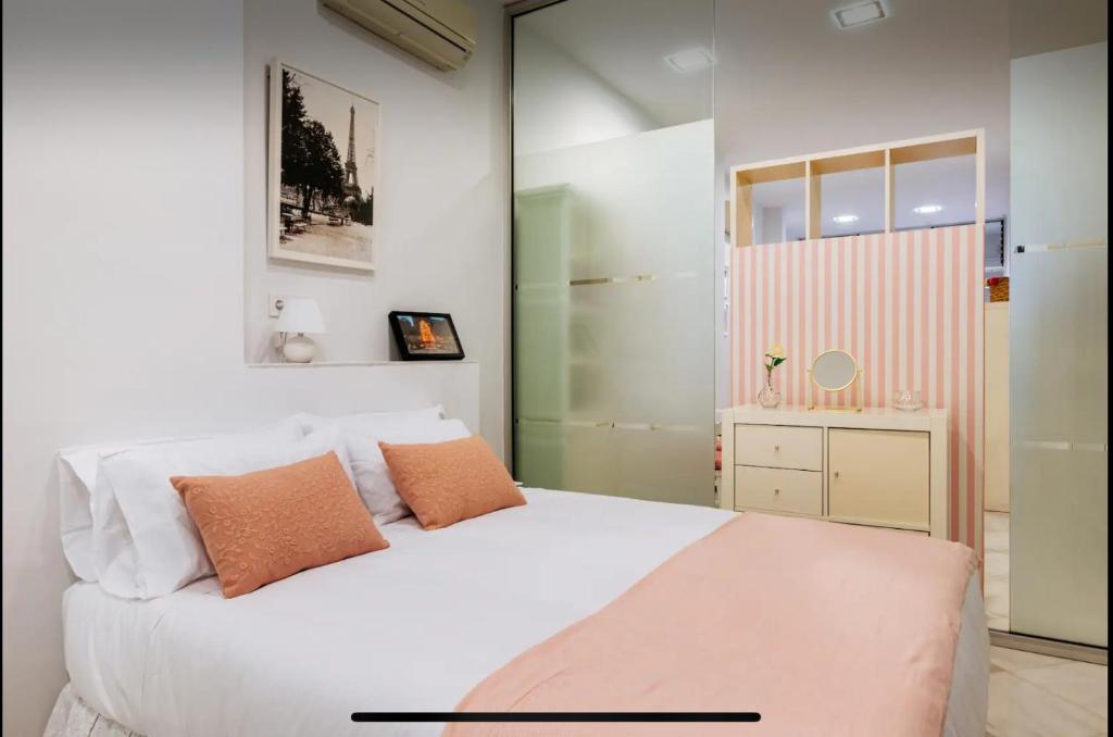 a bedroom with a white bed with orange pillows at Lovely loft junto a la Giralda in Seville