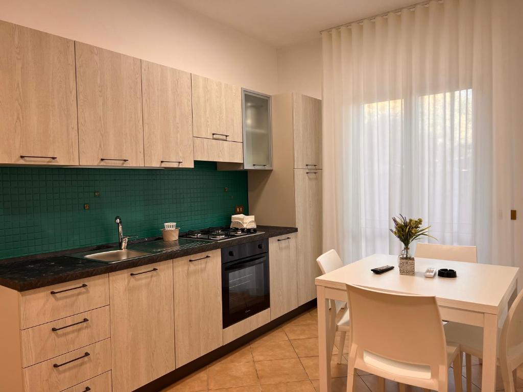 uma cozinha com armários de madeira e uma mesa com uma mesa branca; em Residence Il Pantheon - Zeus em Marina di Fuscaldo