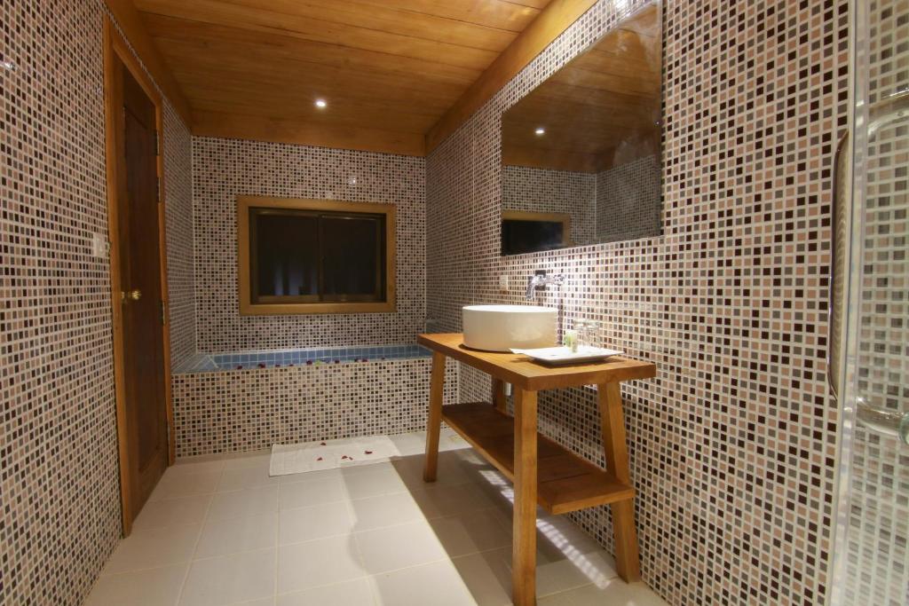 een badkamer met een wastafel en een televisie op een betegelde muur bij Angkor Heart Bungalow in Siem Reap
