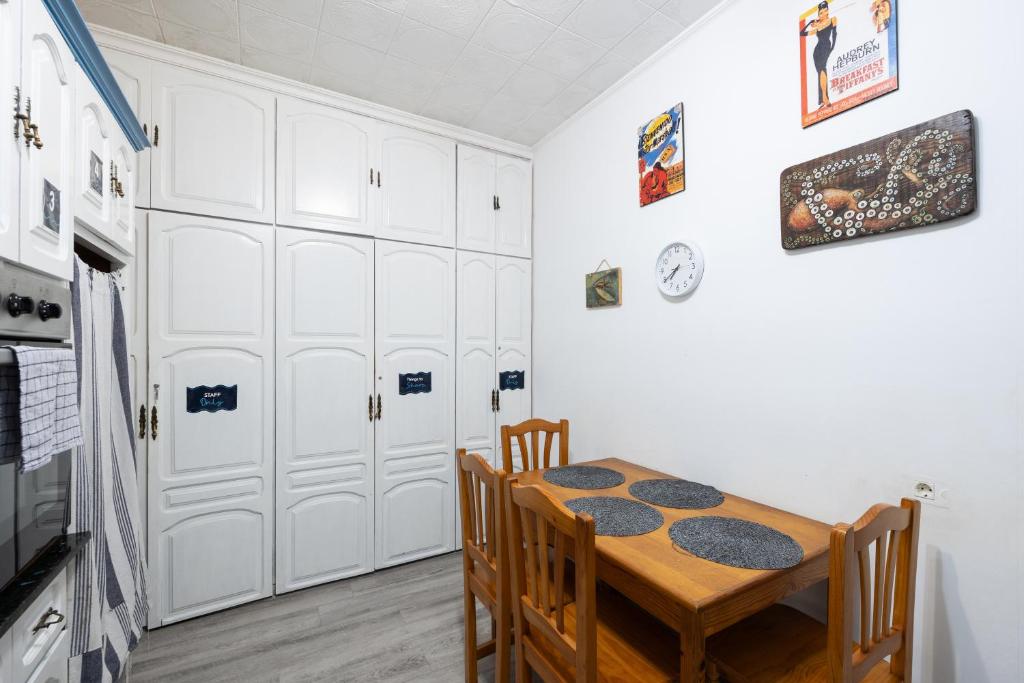 a dining room with a table and chairs and white cabinets at Kite & Surf Nomad House in Las Palmas de Gran Canaria