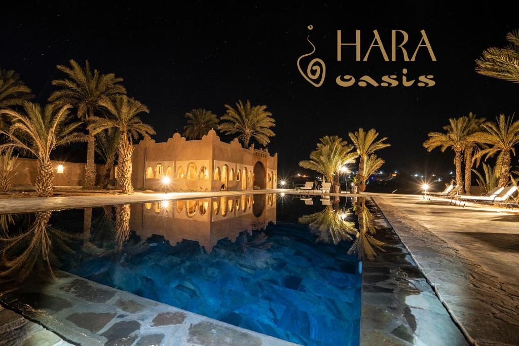 a resort with a swimming pool at night at Lodge Hara Oasis in Agdz