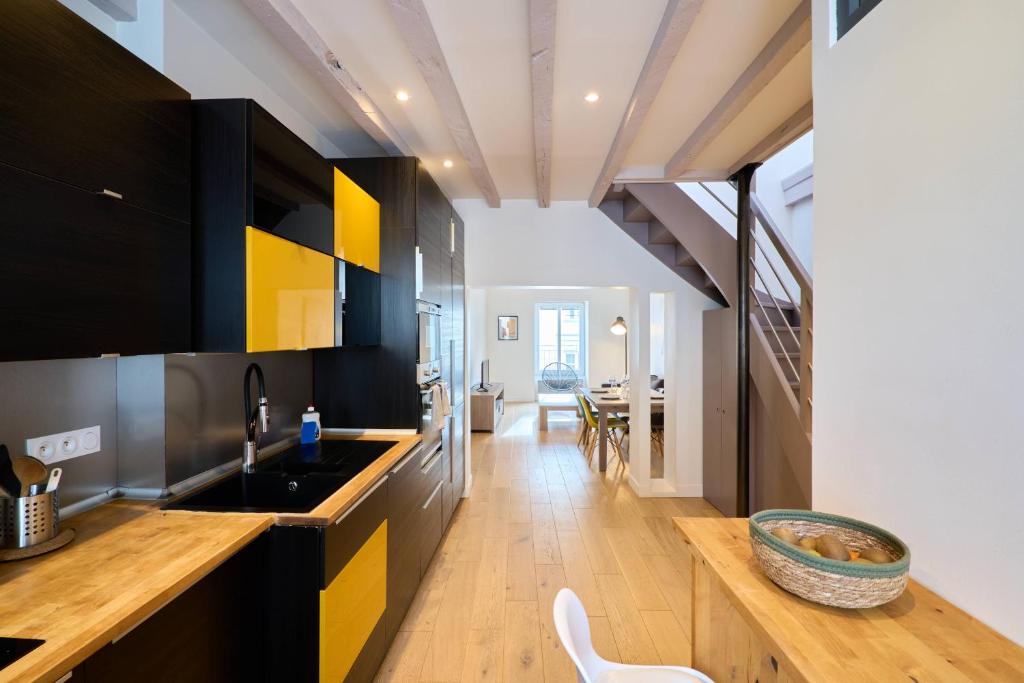 a kitchen with yellow and black cabinets and a dining room at LE BLUM COEUR - Hyper Centre Nantes in Nantes