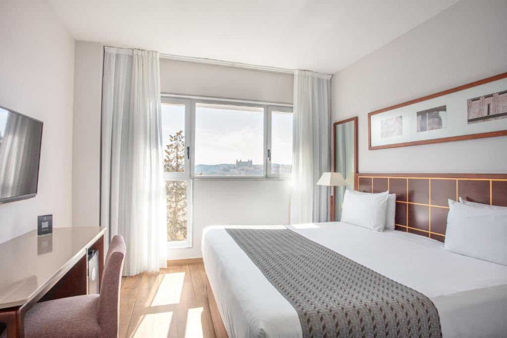 Habitación de hotel con cama, escritorio y ventana en Eurostars Toledo en Toledo