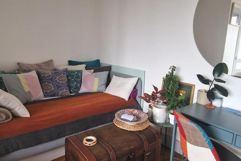 uma sala de estar com um sofá com almofadas e uma mesa em Appartement cosy avec balcon et vue dégagée em Montreuil