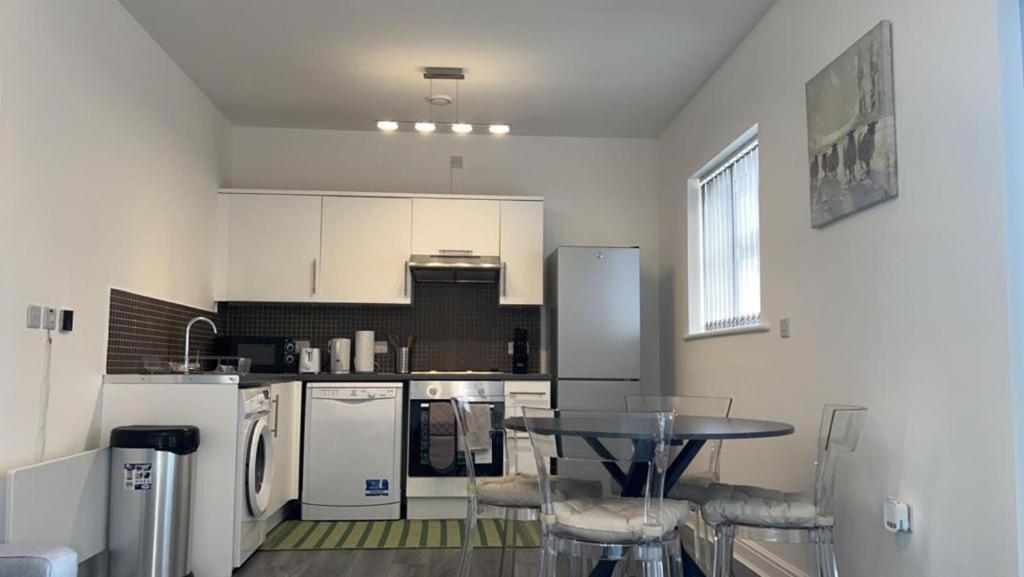 Beautiful 1-Bed Apartment in Tipton في تيبتون: مطبخ به أجهزة بيضاء وطاولة وكراسي