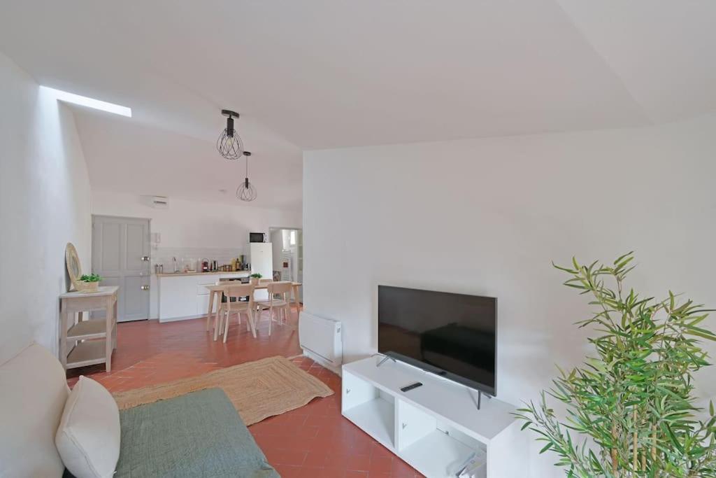 un salon avec une télévision à écran plat sur un mur blanc dans l'établissement Brugnotte - Wi-Fi - Proche THEaTRES, à Avignon