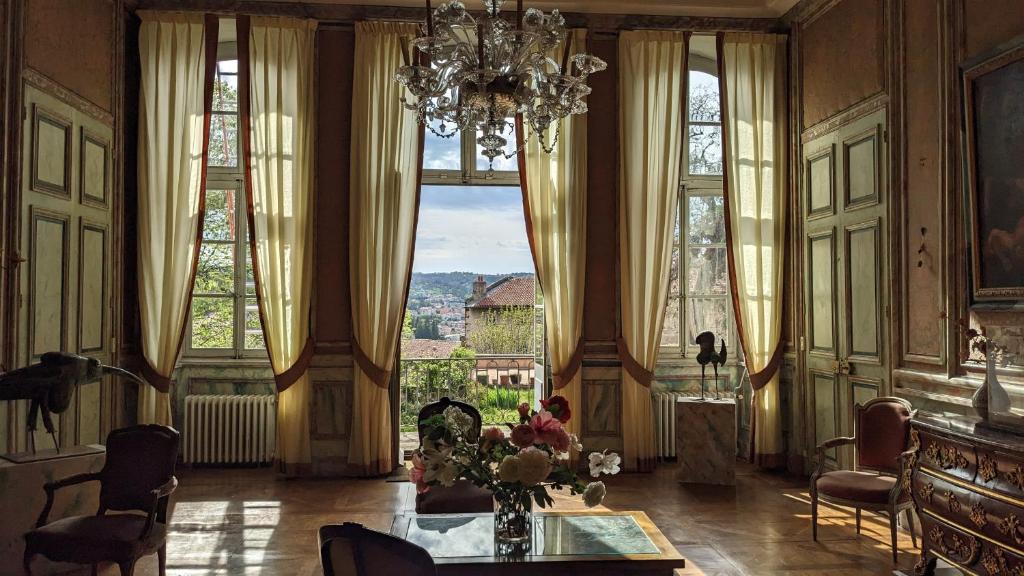 uma sala de estar com uma mesa e um lustre em Maison d'hôtes - Hôtel particulier de Jerphanion Cambacérès em Le Puy-en-Velay