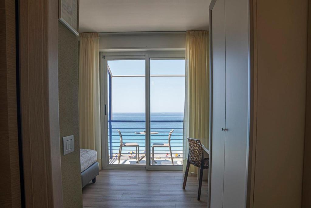 a room with a door to a balcony with a view of the ocean at Hotel 4 Venti spa & wellness in Sestri Levante