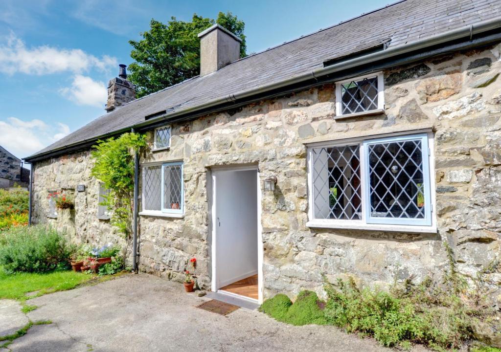 an old stone cottage with a white door at Crown Cottage in Dolgellau