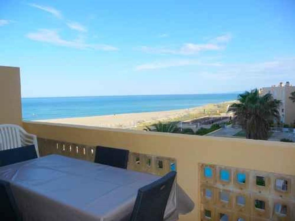 d'un balcon avec une table et une vue sur la plage. dans l'établissement Le Barcarès - Appartement 3 pièces avec piscine et parking proche plage - FR-1-782-7, au Barcarès